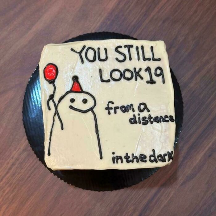 A white rectangular cake with a humorous inscription and a cartoon figure holding a red balloon, one of many amazing treats from bakers.