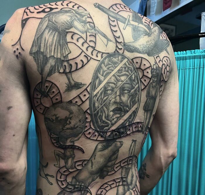 Intricate back tattoo art featuring ancient figures, snakes, and a Medusa head, showcasing inspiring tattoo art.