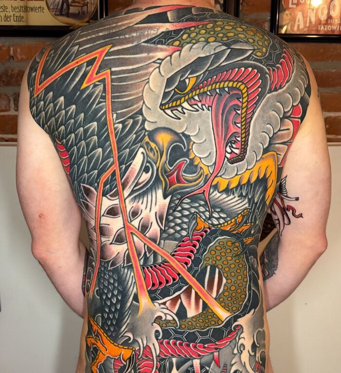 Full back tattoo art depicting a fierce dragon and snake in traditional style, an inspiring example of tattoo art.