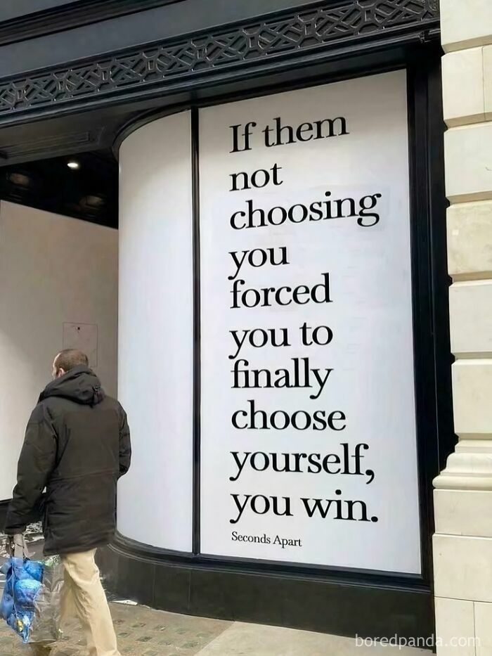 A man walking past a large window display with the wholesome quote: If them not choosing you forced you to finally choose yourself, you win.