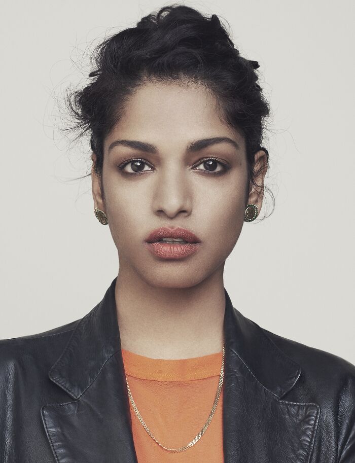 M.I.A. looking directly at the camera. Her career highlights include innovative music and fashion.