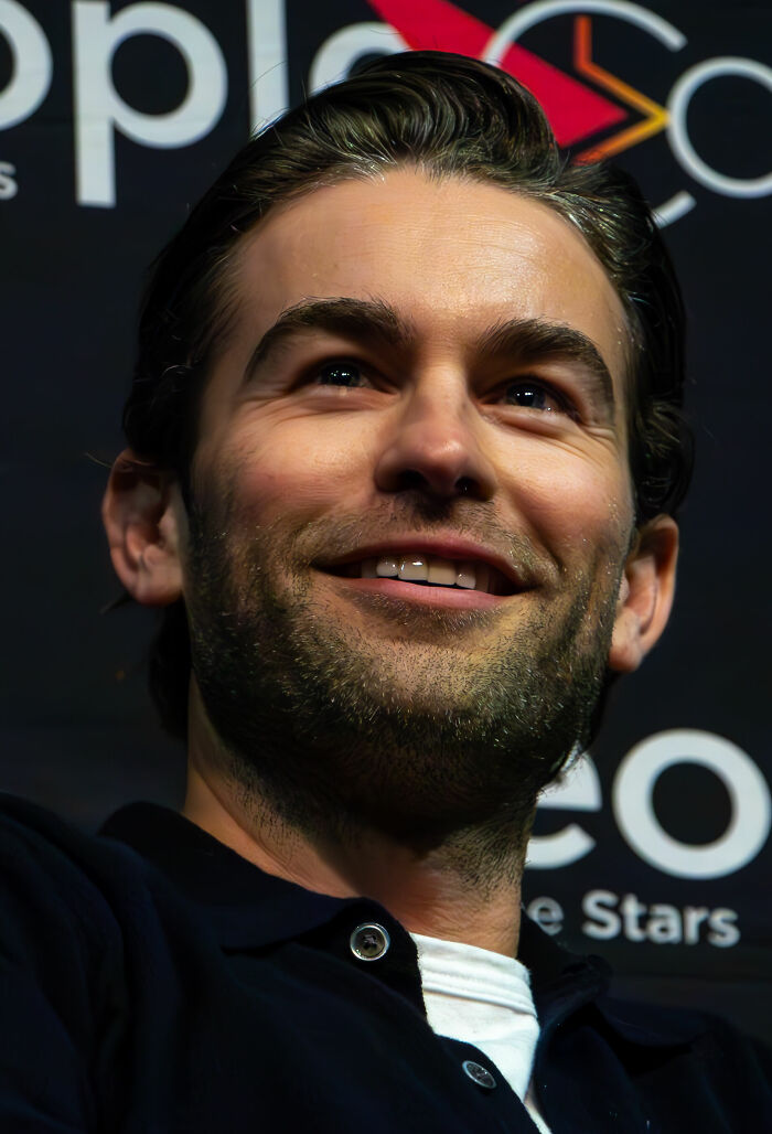 Chace Crawford career highlights: close-up of the actor smiling, looking up, with a beard and dark hair.