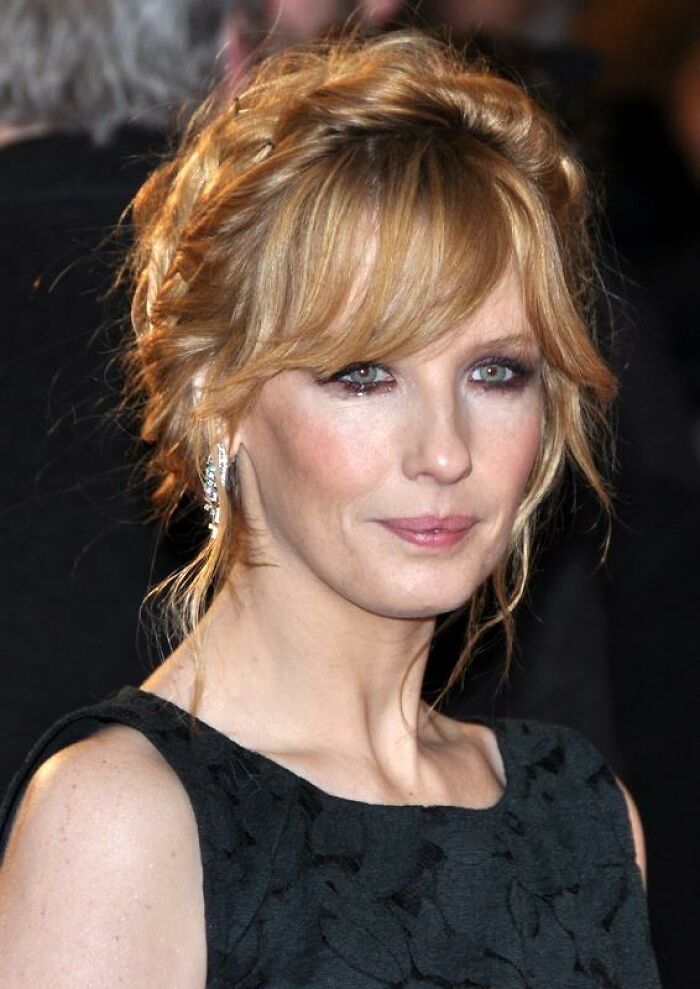 A close-up shot of Kelly Reilly, featuring her blonde hair, blue eyes, and light makeup. Her career highlights include Yellowstone.