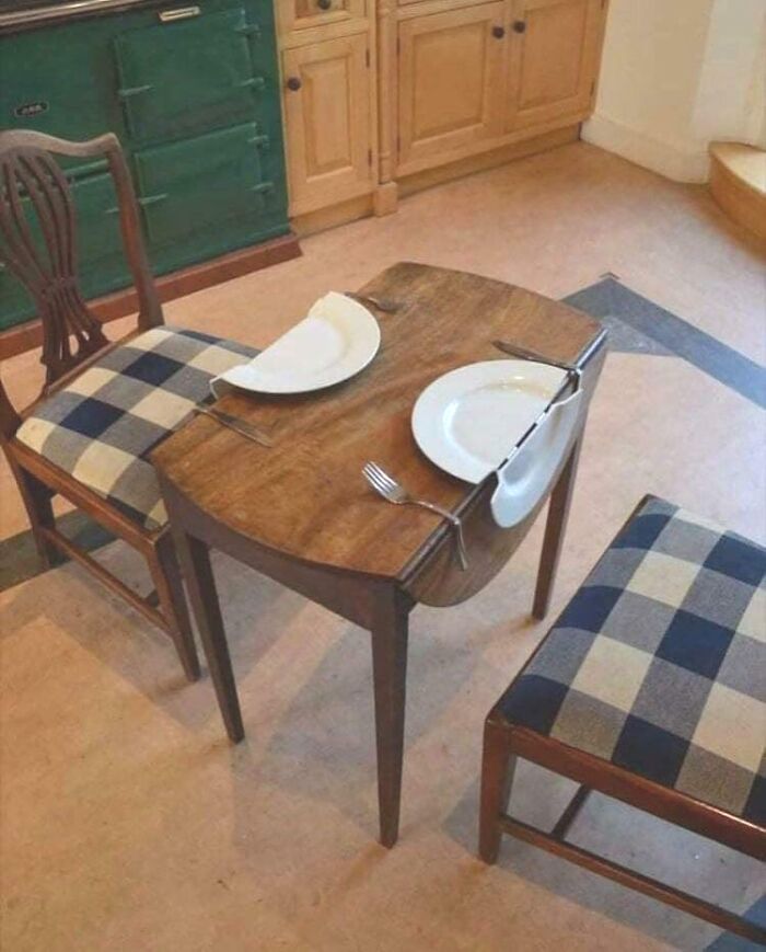 A bizarre wooden dining table, created by furniture designers, featuring two half-moon sections that wrap around seated diners.