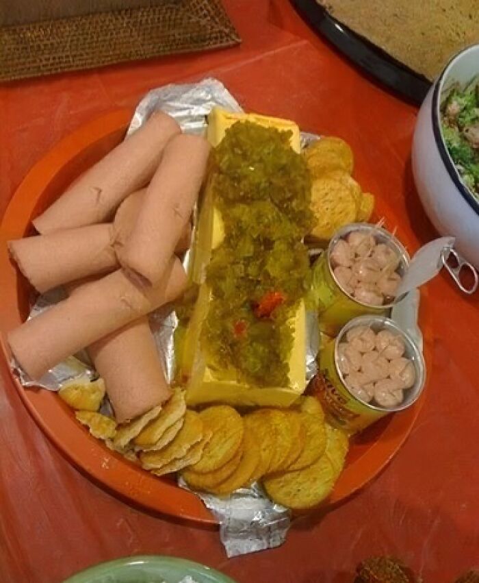 A platter with hot dogs, crackers, a block of cheese with relish, and canned beans, an example of disgusting food.