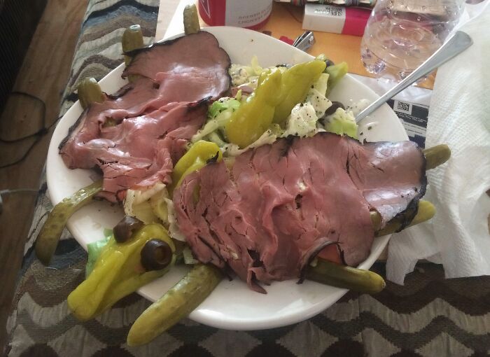 A plate of disgusting food: sliced roast beef, salad, and pickles arranged to resemble a turtle.