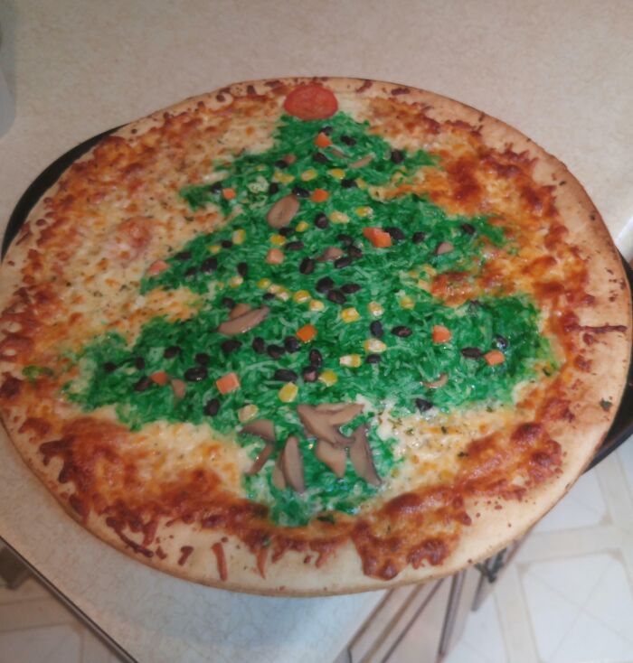 A pizza decorated with green topping and various vegetables to look like a Christmas tree, an example of disgusting food.
