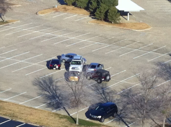 Aerial view of outrageous parking with multiple cars haphazardly parked in a large empty lot.