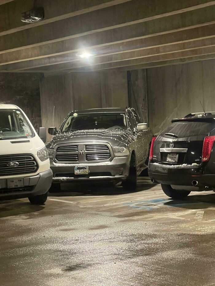 A pickup truck decorated with lights, parked improperly between two other vehicles, an example of outrageous parking.