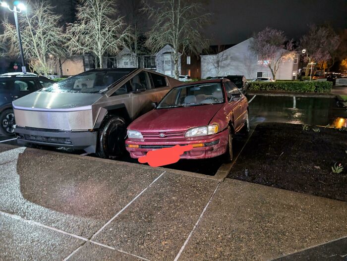 A metallic gray Tesla Cybertruck and a red car parked very close, illustrating outrageous parking.