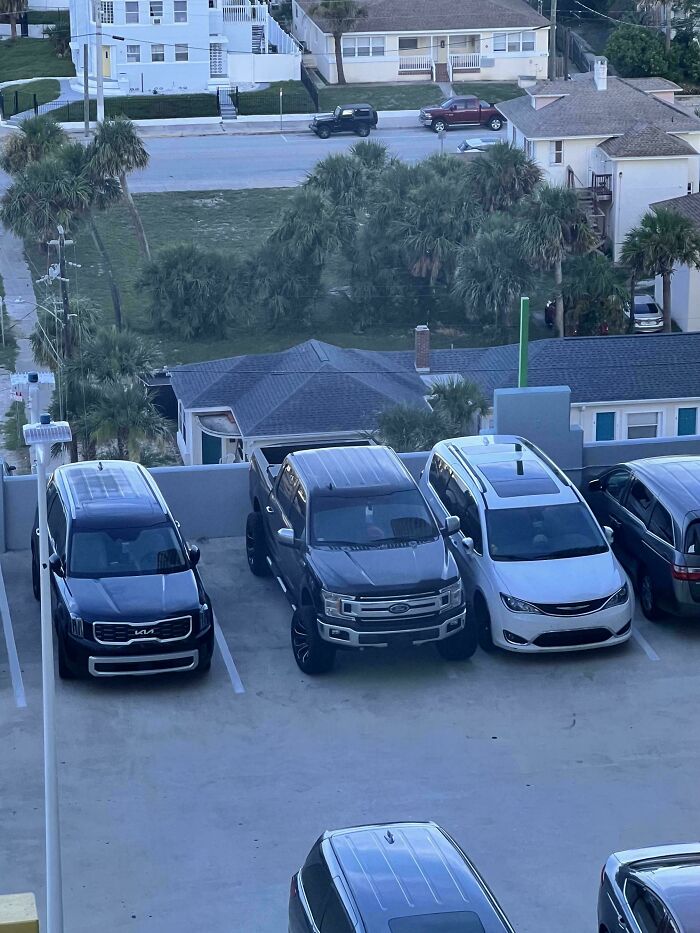 An overhead view shows cars parked in a lot, one truck taking up two spots, an example of outrageous parking.