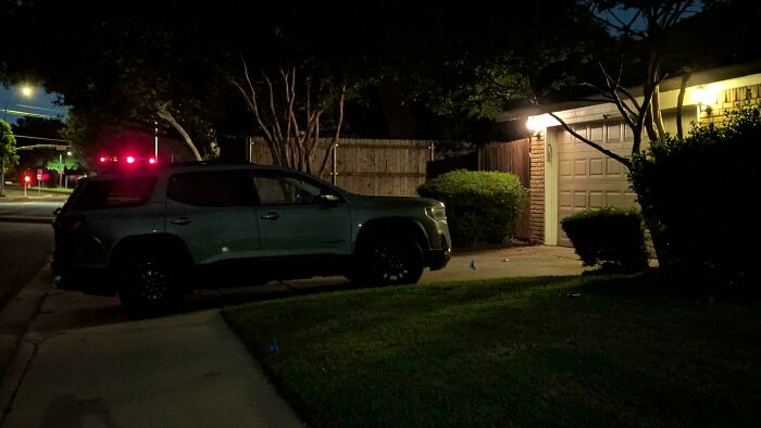 A grey SUV with red brake lights on is parked crookedly in a driveway at night, showcasing outrageous parking.