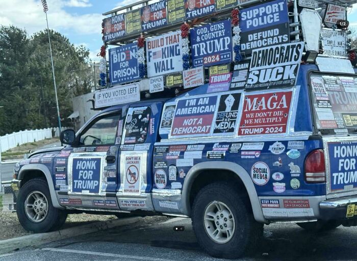 A truck covered in political signs demonstrating outrageous parking, making it hard for others.
