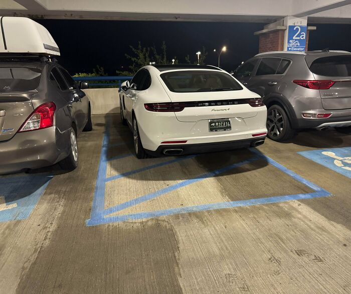 A white Porsche parked incorrectly, taking up more than one spot, demonstrating outrageous parking.