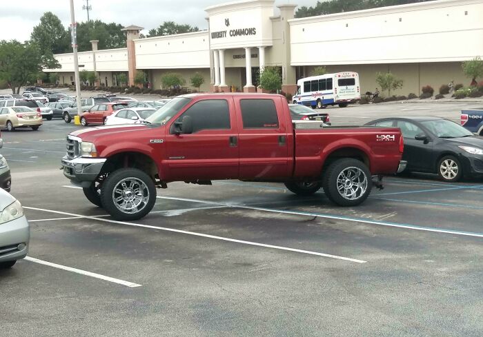 A large red truck parked across multiple spaces, showcasing outrageous parking.