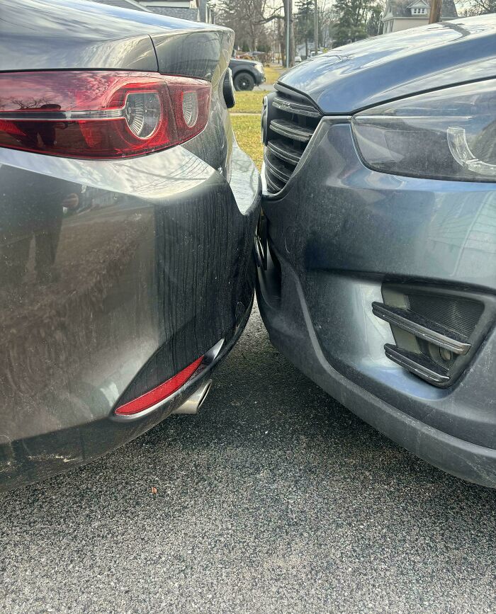 Two cars are bumper-to-bumper, nearly touching, illustrating an instance of outrageous parking.