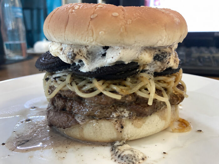 Disgusting food photo of a bizarre burger with ice cream, Oreo cookies, and spaghetti on a bun.