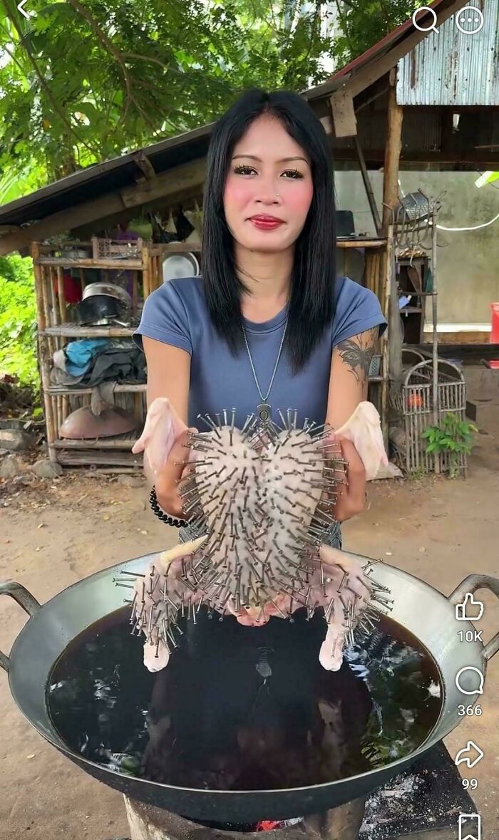A woman holding a raw chicken covered in nails over a pot of oil, representing disgusting food.