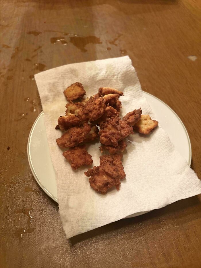 Disgusting food: Fried chicken pieces resting on a paper towel on a white plate, appearing greasy.