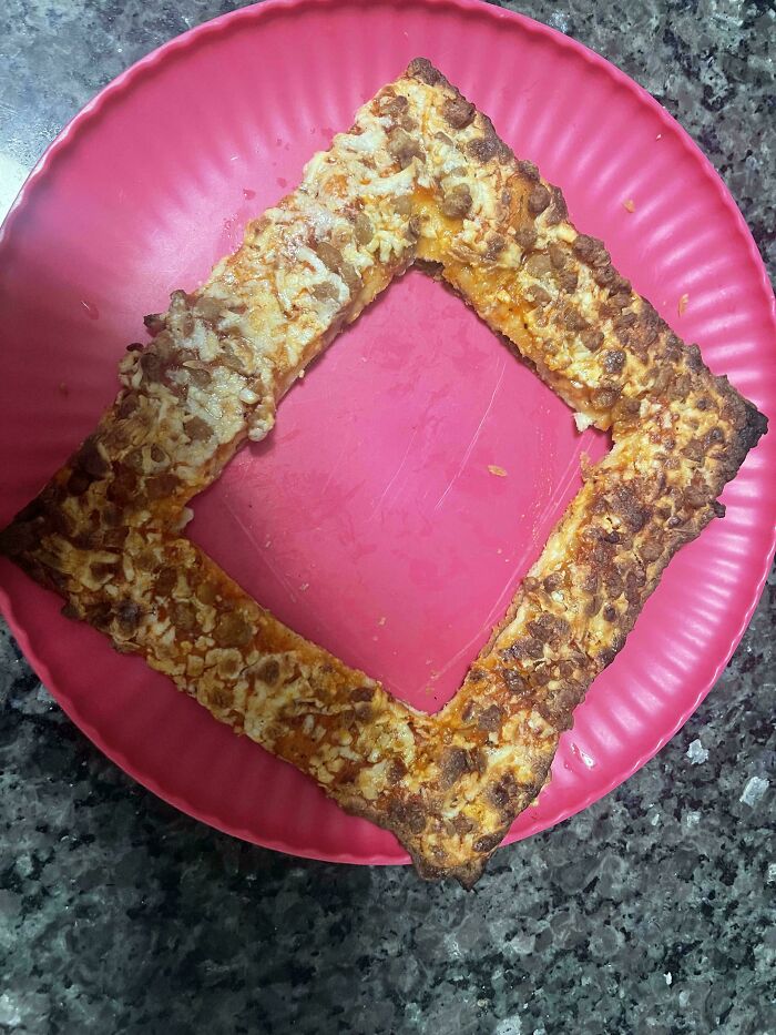 Disgusting food: A square pizza crust, with the center removed, topped with cheese and sausage on a pink plate.