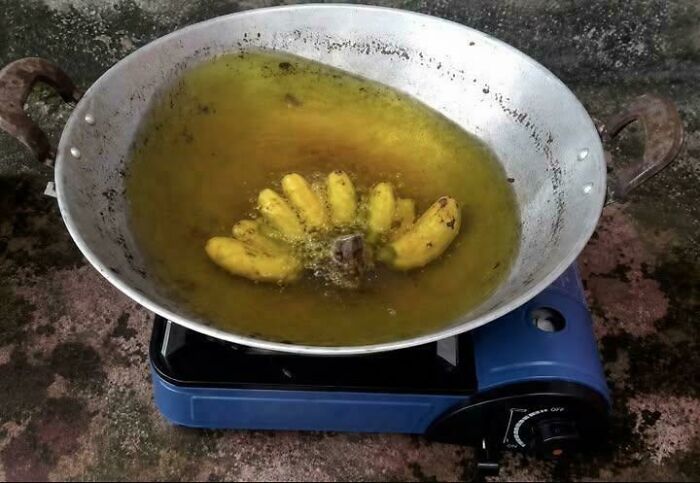 Bananas frying in a pan of oil on a portable gas stove, an example of stupid and disgusting food.