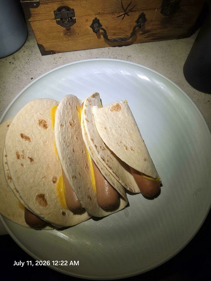 A plate of disgusting food: hot dogs with melted cheese wrapped in tortillas, poorly prepared.