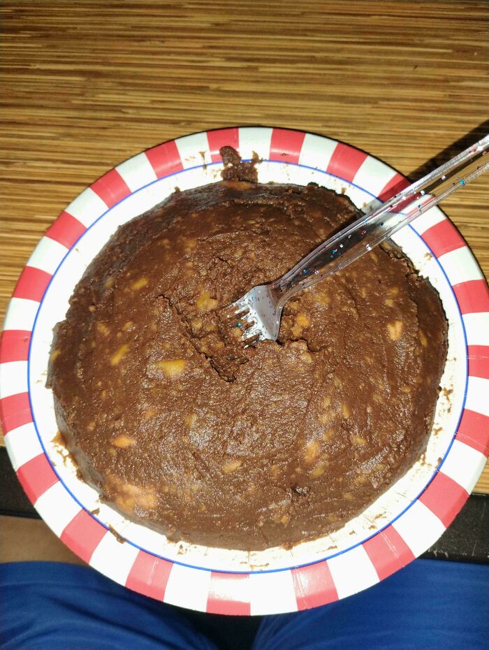 A chocolate cake-like dessert with a fork stuck in it on a red and white striped plate, an example of disgusting food.