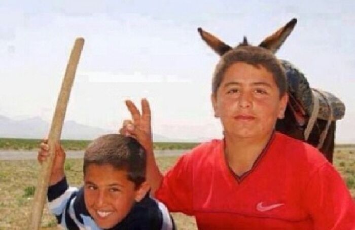 Two boys posing for a photo, one holding a stick, the other with a donkey behind him, creating a 'When You See It' optical illusion.