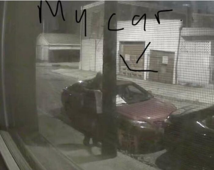 A night-time view through a window showing a red car parked, with My car written on the glass, illustrating outrageous parking.