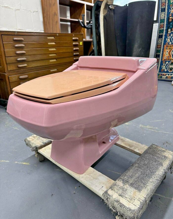 A pink vintage toilet with a wooden seat, a distinct piece of 1970s and 1980s interior design.