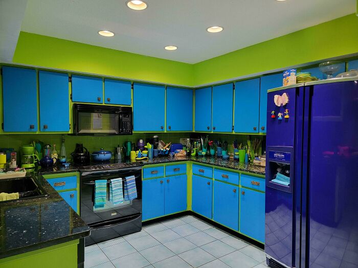 Vibrant 1970s interior design kitchen with bold blue cabinets and neon green walls, showcasing a unique style.