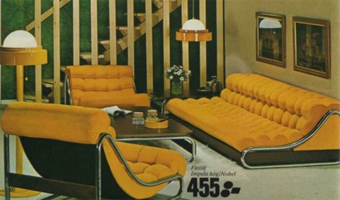 A living room showing 1970s and 1980s interior design with orange tufted furniture and striped wall panels.