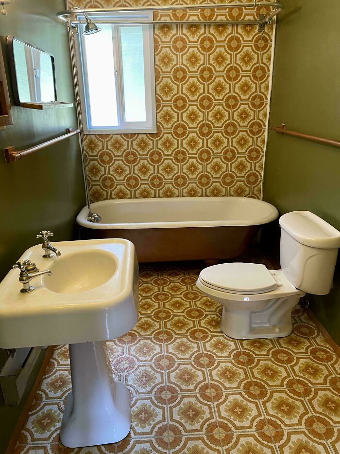 A bathroom from the 1970s and 1980s, featuring patterned wallpaper and tile reflecting interior design trends.