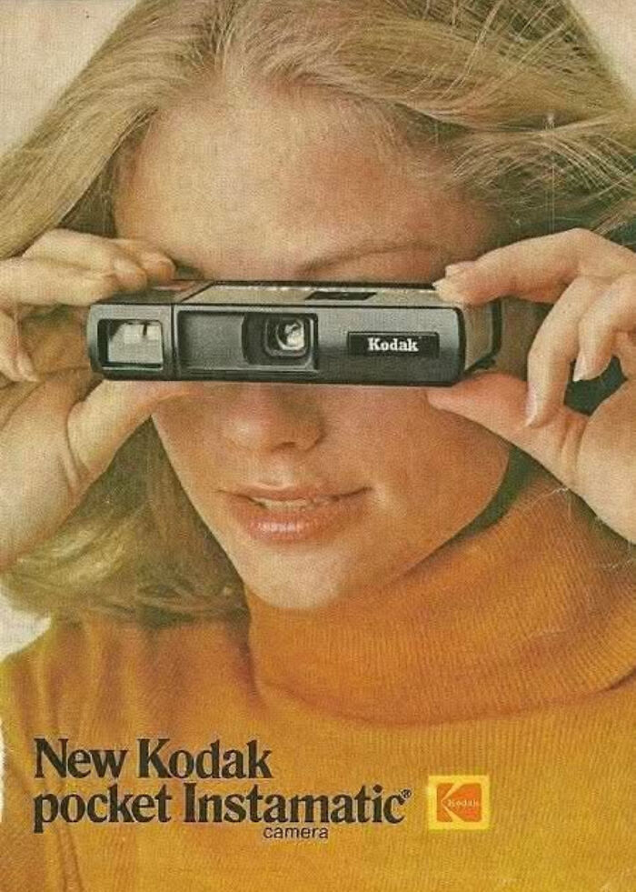 A woman holding a Kodak Instamatic camera, reflecting the technology and style of the 1970s and 1980s.