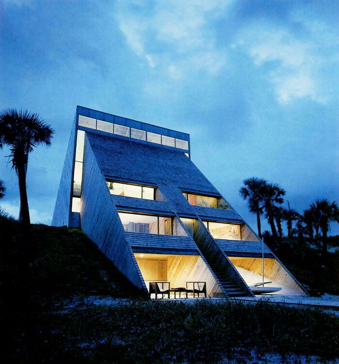 A striking A-frame house at dusk, exemplifying the unique architectural interior design from the 1970s and 1980s.