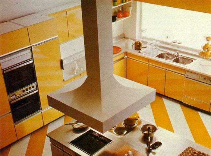 A vibrant 1970s interior design kitchen with yellow striped floor and cabinetry, featuring a large central island.