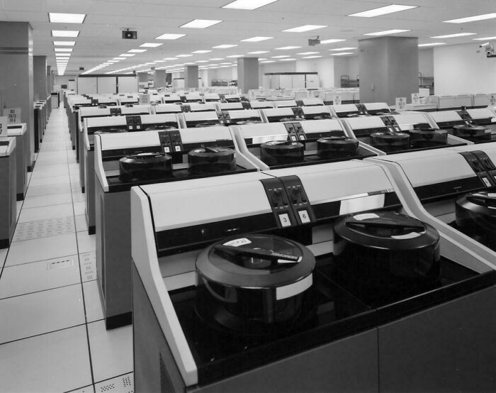 A large room filled with rows of vintage computer equipment, capturing the essence of 1970s and 1980s interior design for a data center.