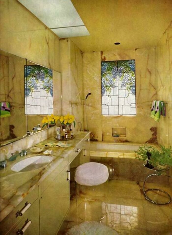A luxurious 1980s interior design bathroom with marble walls, stained-glass windows, and a large bathtub.