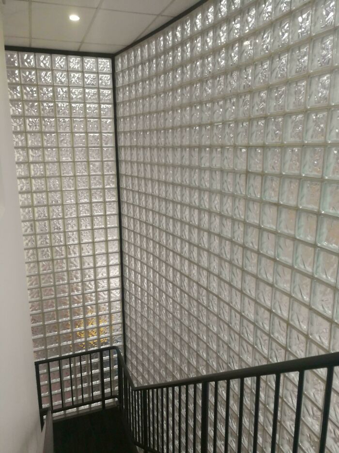 A staircase alongside a large wall made of glass bricks, a popular element in 1970s and 1980s interior design.