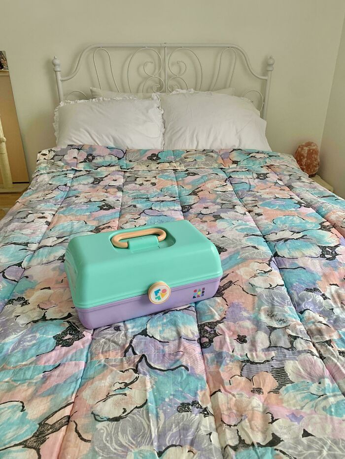 A pastel floral comforter on a bed, with a teal and lavender case, reflecting 1980s interior design aesthetics.