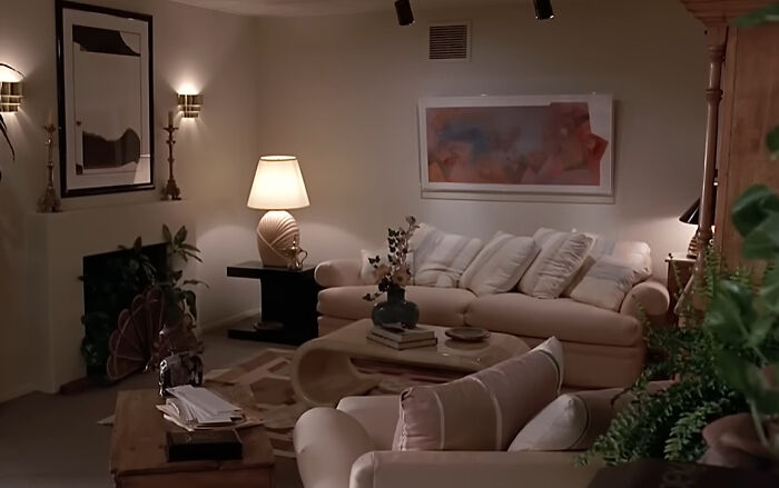 A cozy 1970s interior design living room with a cream sofa, patterned rug, and warm lighting.