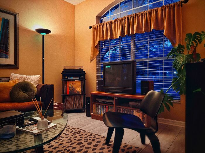 A cozy living room showcasing 1970s and 1980s interior design with a vintage TV, record player, and warm lighting.