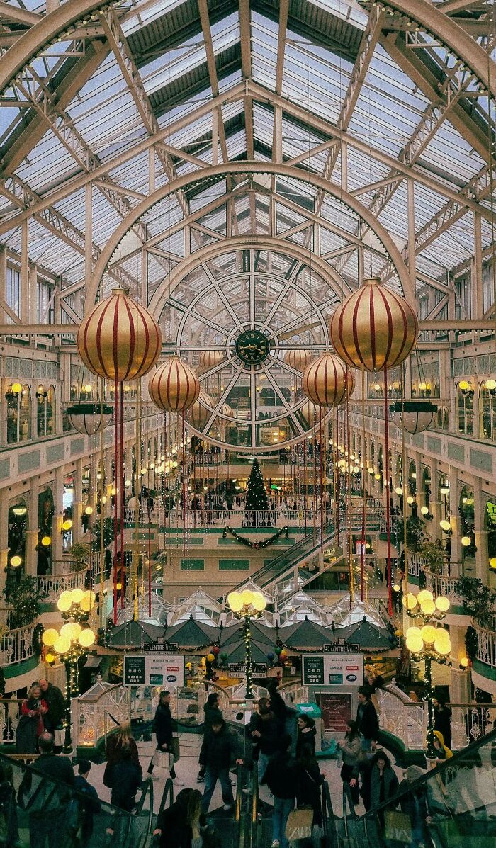 A grand hall with 1970s and 1980s interior design, featuring ornate architecture and large hanging ornaments.