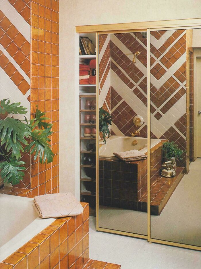 A bathroom with geometric orange and white tiles, showcasing 1970s and 1980s interior design.