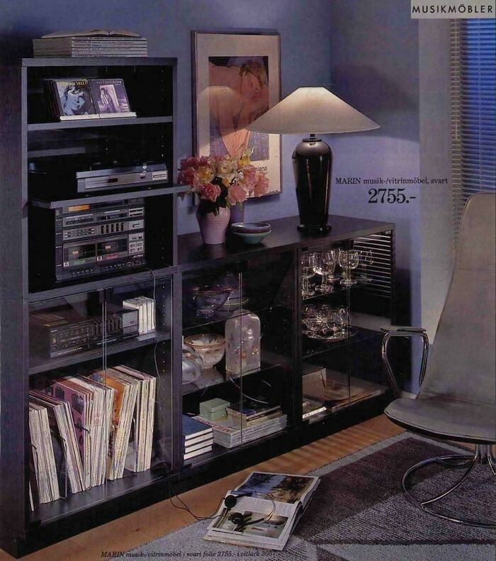 A living room with a stereo system, records, and a lamp, demonstrating 1970s and 1980s interior design.
