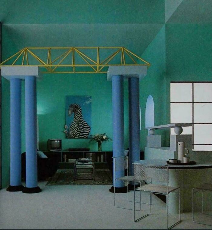 A distinctive 1980s interior design living space with teal walls, blue pillars, and a unique architectural element.