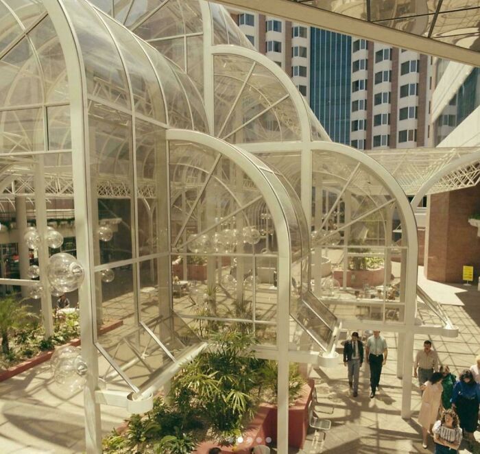 A grand atrium showcasing striking 1980s interior design with soaring glass and white structural arches.
