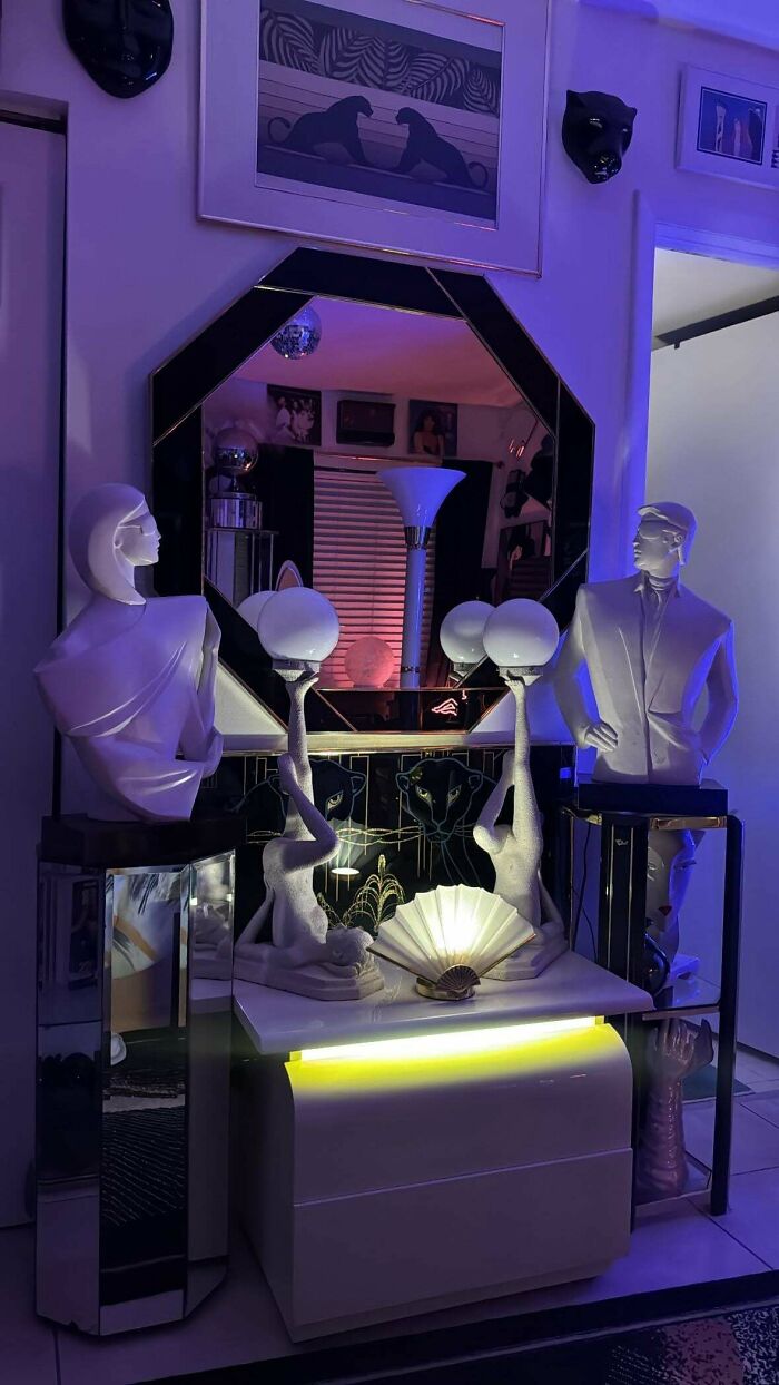 A display of 1970s and 1980s interior design featuring stylized busts, mirrored furniture, and purple lighting.