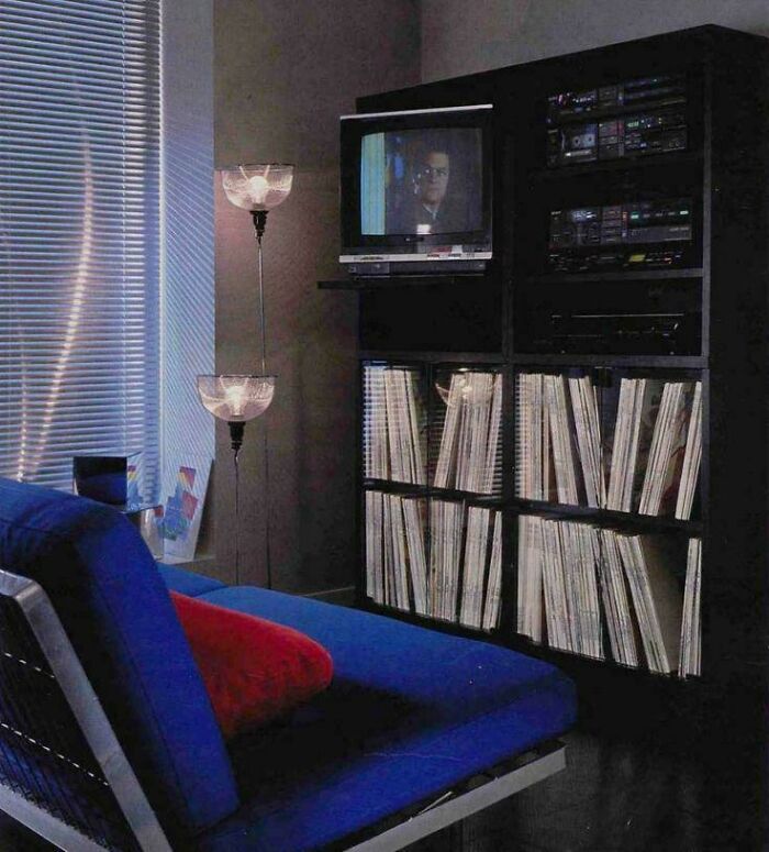 A cozy 1970s interior design with a blue sofa, record collection, and a TV, showcasing vintage style.