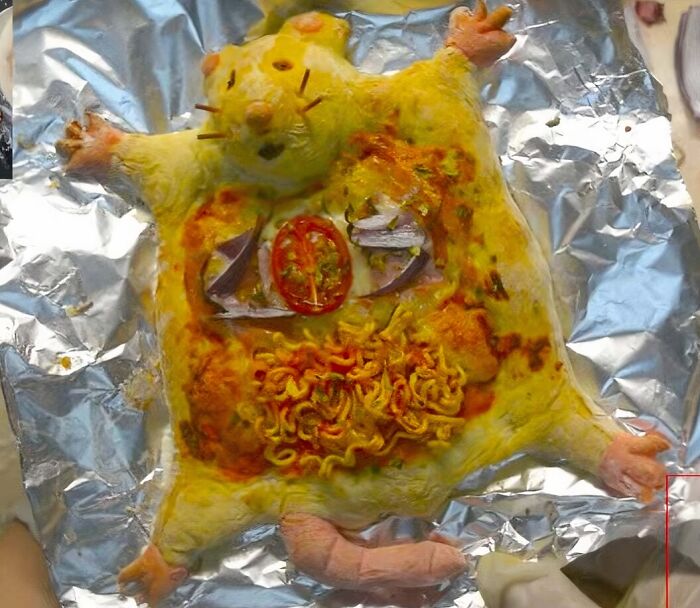 An overhead shot of disgusting food, a cooked whole rodent-shaped meal with ramen and vegetables.